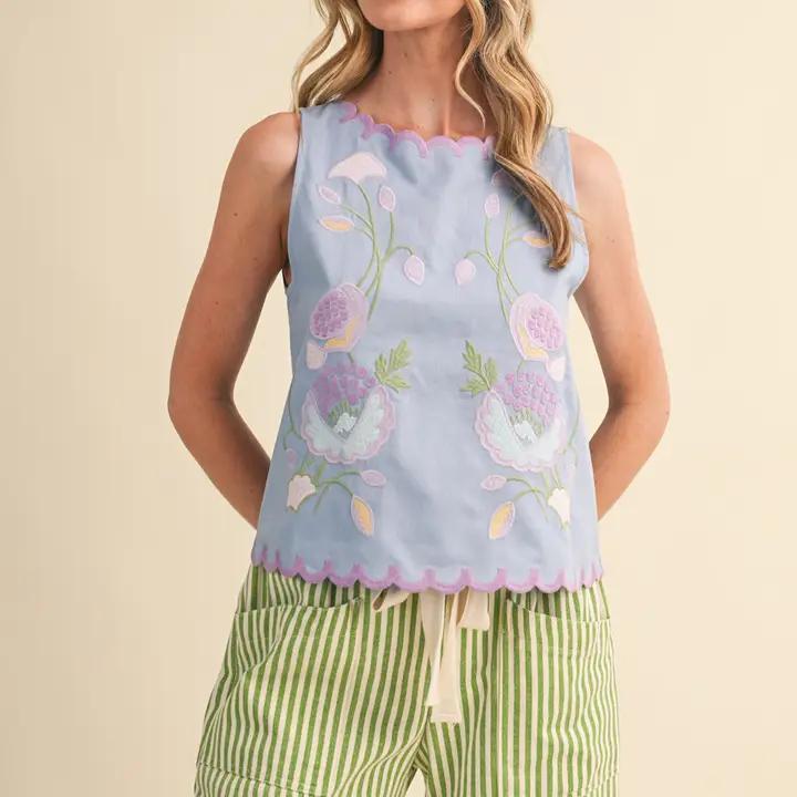 Woman wearing blue tank top and green striped pants against creme background.