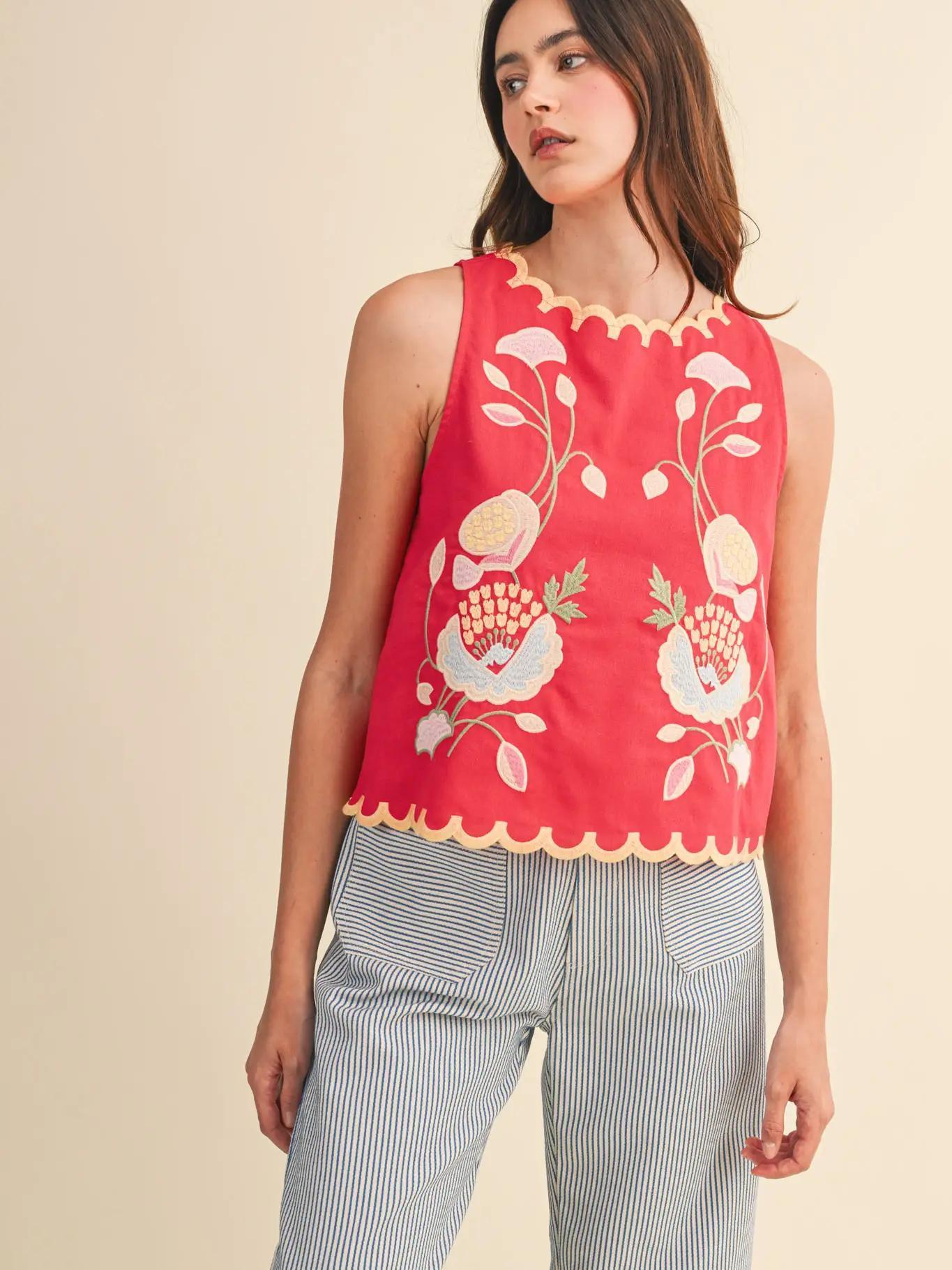 Woman wearing red tank top and striped pants against creme background.