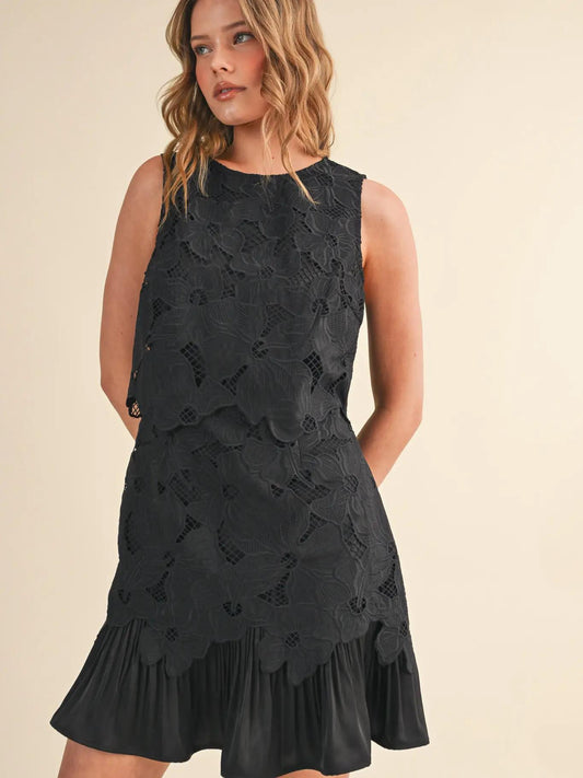 Woman wearing black mini dress against white background.