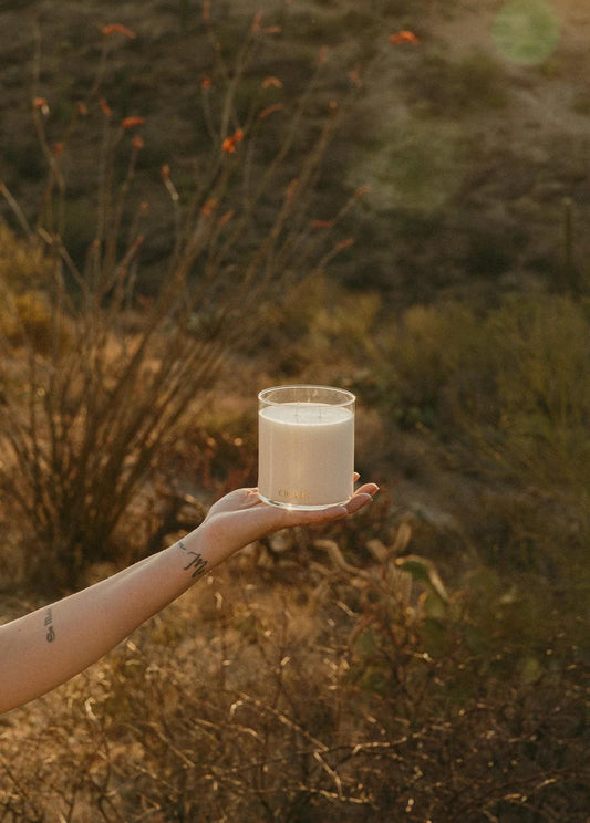 hand holding white two wick candle against desert background