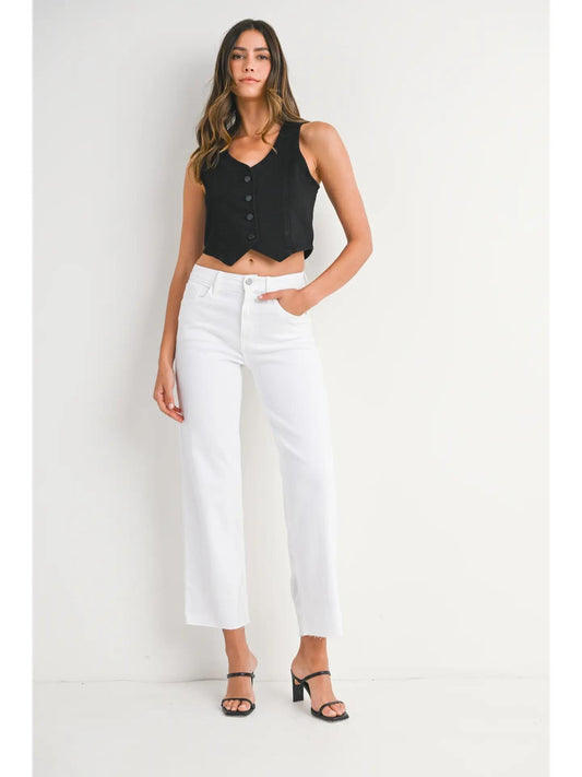 Woman wearing white jeans a black tank top and black heels. 