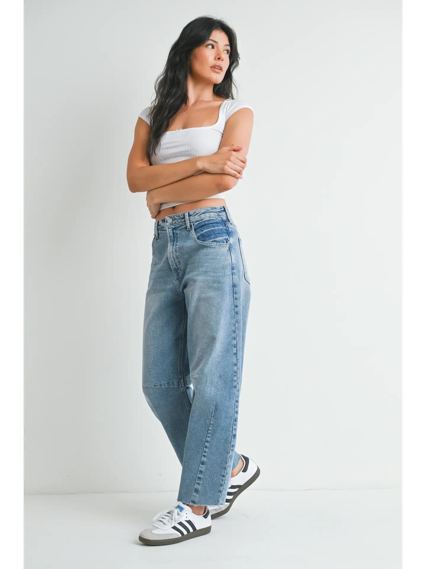 Light wash barrel jeans worn with a white crop tee and black and white sneakers. 