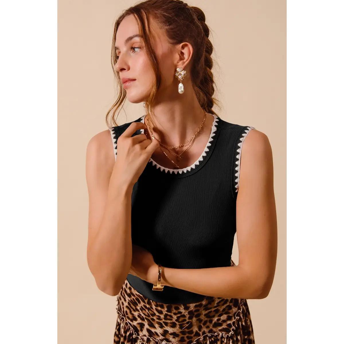 Woman wearing black tank with white detail and a cheetah print skirt. 