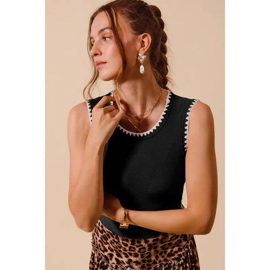 Woman wearing black tank with white detail and a cheetah print skirt. 