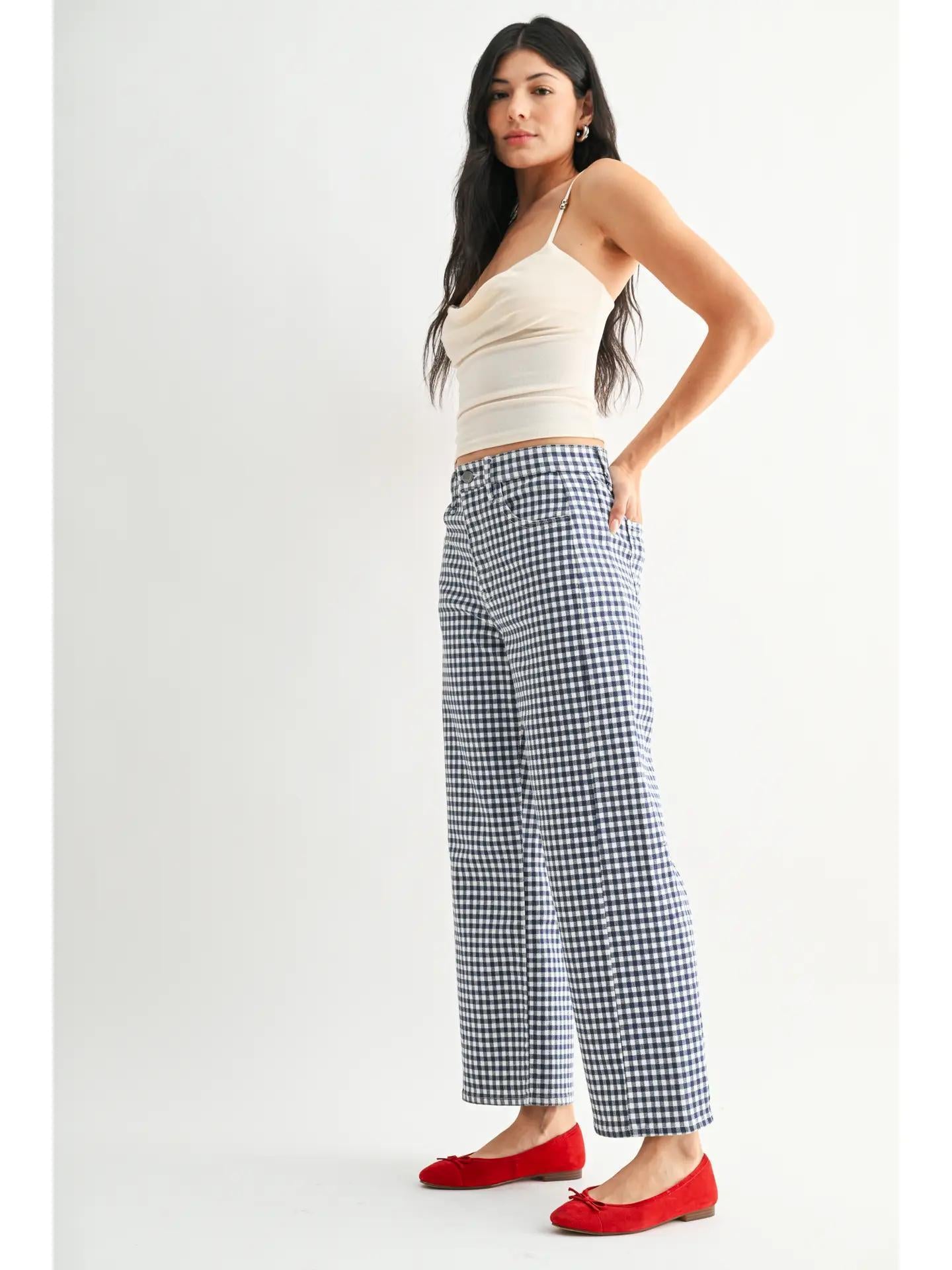 Woman wearing navy gingham jeans a white tank top and red ballet flats. 