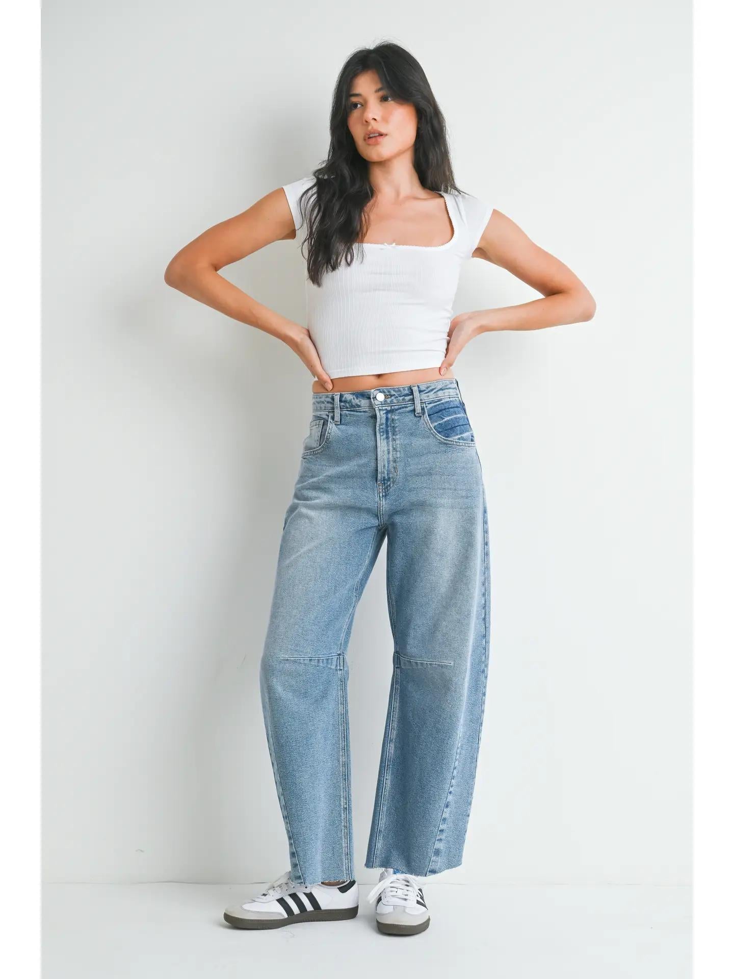 Light wash barrel jeans paired with a white basic top and white and black sneakers. 